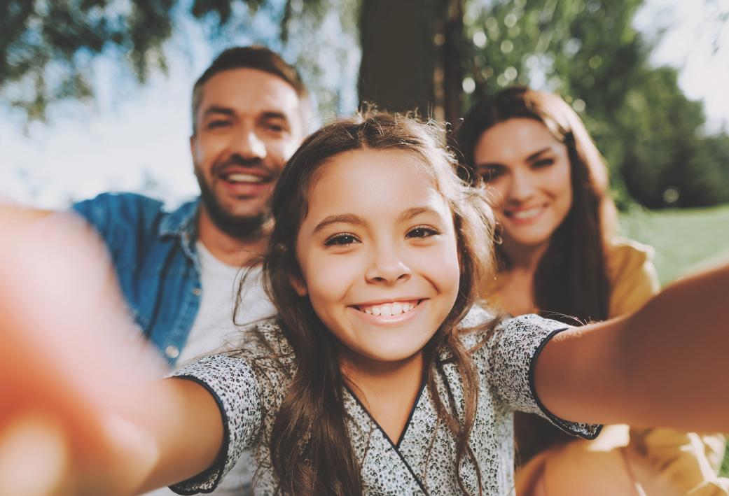 Kindje met ouders Een klein meisje die een selfie neemt samen met haar papa en mama in een park.
